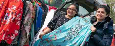 2 visitors to Bowlee Car Boot Sale and Market examining a dress.