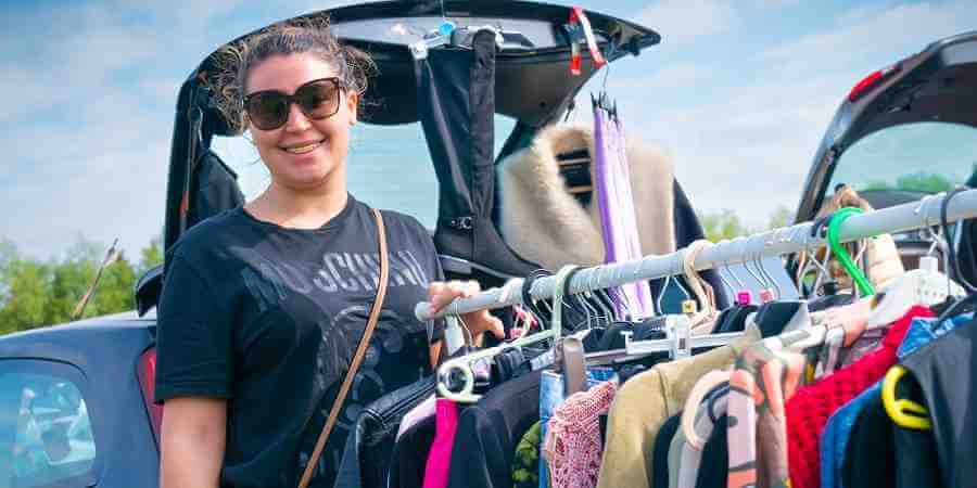 Customer at car boot sale with a rack of clothes.