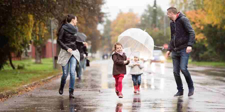 A family with children walking down the street on a rainy day.