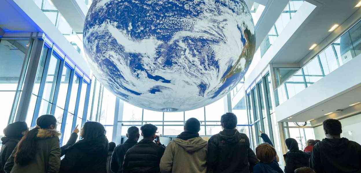 Visitors at Rochdale Central Library standing under the huge globe forming part of the Gaia exhibition.