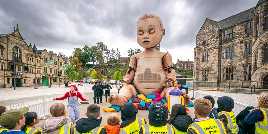 Pupils listening to an educational talk in front of an 8.5 metre tall baby sculpture.