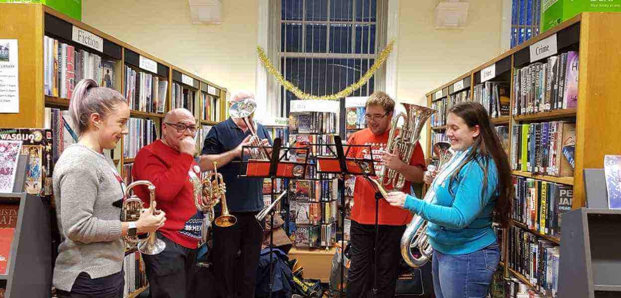 Players with brass instruments performing in Littleborough Library.