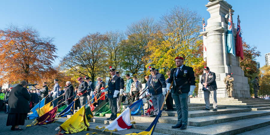 Veterans standing at Rochdale Cenotaph with flags lowered.