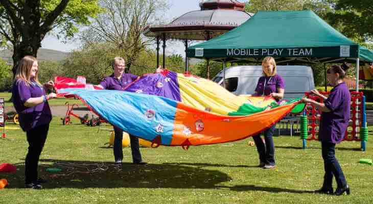 Council staff holding a large multicoloured piece of fabric.