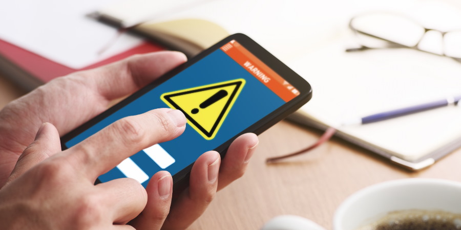 Hand about to press a smartphone screen with a warning triangle on it.