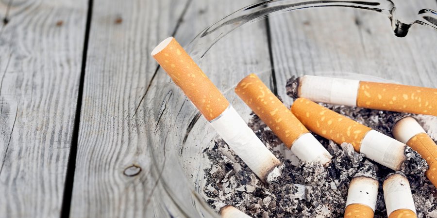 Used cigarettes in a glass ashtray.