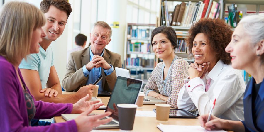 A group of mature students talking in the library.