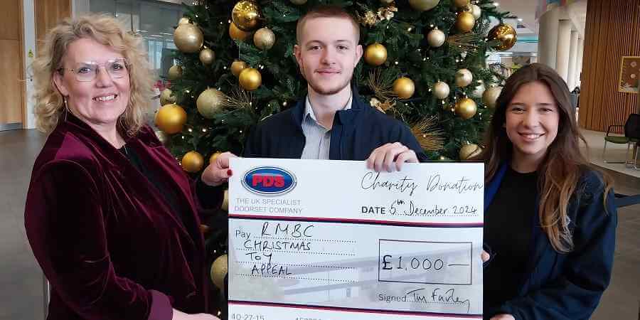 Helen Walton with Lewis and Zoe from PDS Doorsets, Lewis holds a large cheque for one thousand pounds.