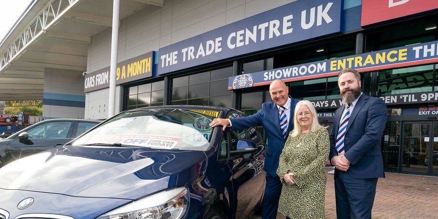 Councillor Sue Smith and 2 Trade Centre UK employees next to a car.