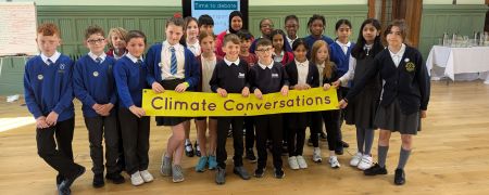 School pupils holding a banner that says 'Climate Conversations'