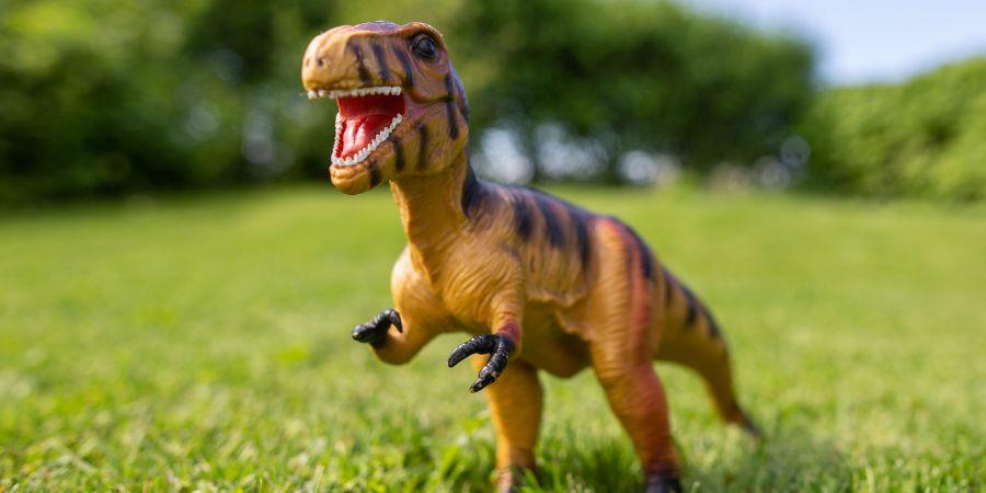 A toy dinosaur in a field.