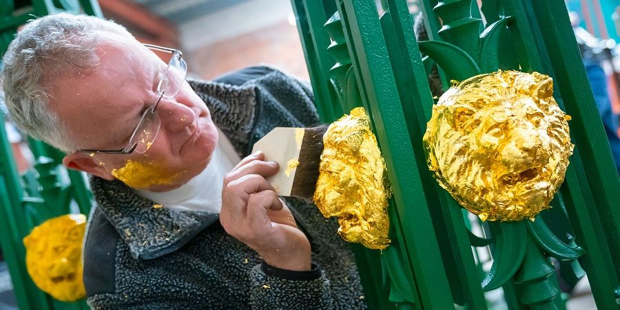 A man applying gold leaf part of Queens Park Bridge