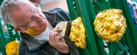 A man applying gold leaf to part of Queens Park Bridge.