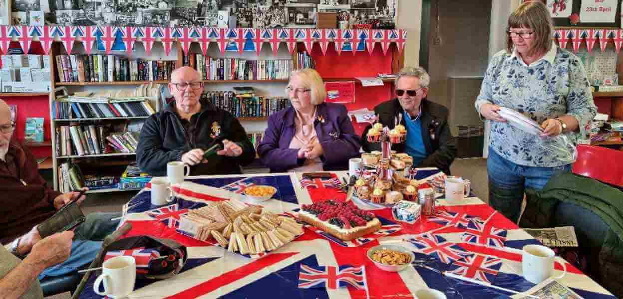 Veterans sat a table draped in a Union flag and set with food.