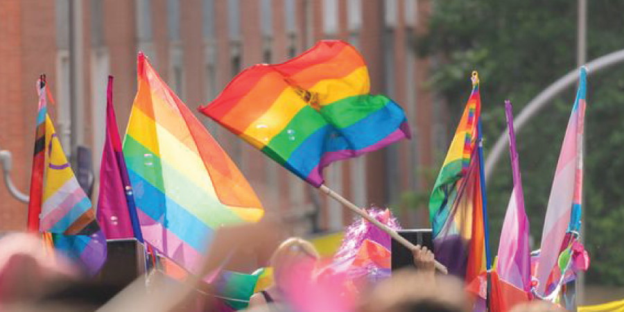 A crowd waving rainbow Pride flags.