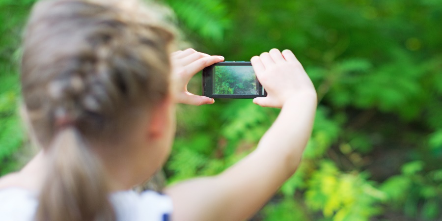 Child taking a picture with a smartphone camera.