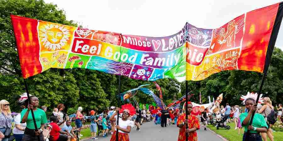 A large multicoloured banner carried at a Feel Good Family Picnic.